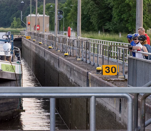 Radfahrer beobachten Schleusung eines Güterschiffes in der Schleuse Hausen