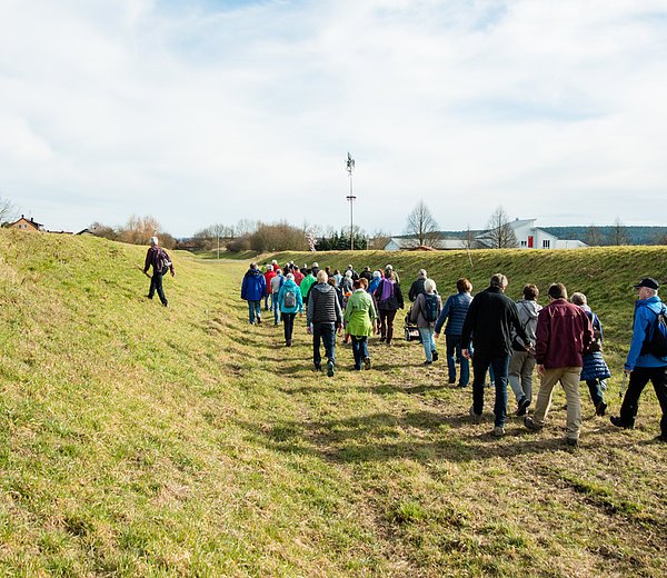 Wandergruppe durchquert das heute trockene Kanalbett des historischen Ludwigkanals in Neuses a.d.R. bei einer Wanderung auf dem Sieben-Flüsse-Wanderweg