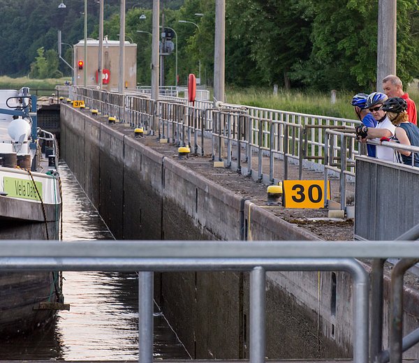 Radfahrer beobachten Schleusung eines Güterschiffes in der Schleuse Hausen